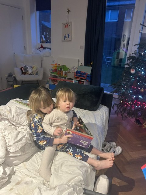 Cara and Eliza reading in bed by the Christmas tree